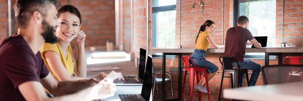 colagem de empresária alegre olhando para colega de trabalho usando laptop com tela em branco no escritório
 - Foto, Imagem