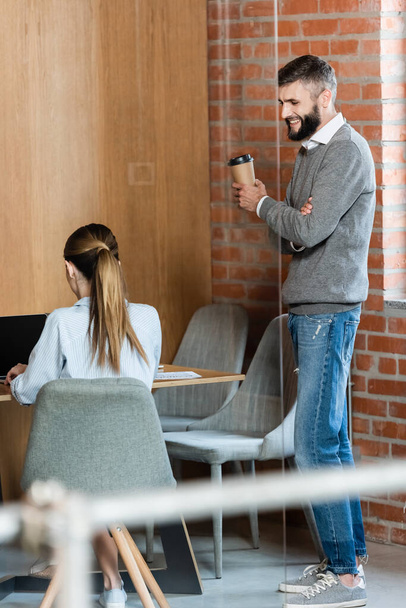 вибірковий фокус щасливого бізнесмена, що тримає паперовий стаканчик і дивиться на колегу
  - Фото, зображення