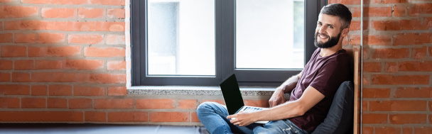horizontal image of happy businessman using laptop with blank screen  - Fotó, kép