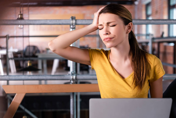 dissatisfied businesswoman with closed eyes touching head near laptop  - Foto, Imagen