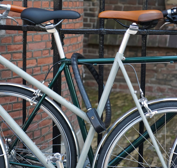 two classical  bicycles standing on lock at black metal fence. european street. modern bicycle . Haag, Netherlands. - Fotó, kép