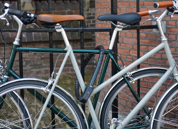 two classical  bicycles standing on lock at black metal fence. european street. modern bicycle . Haag, Netherlands. - Foto, immagini