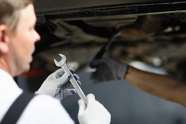 Крупним планом чоловік тримає ключ під час ремонту машини
 - Фото, зображення