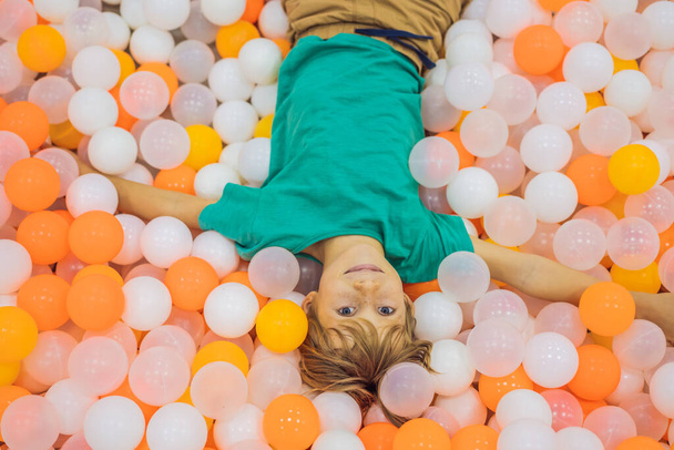 Child playing in ball pit. Colorful toys for kids. Kindergarten or preschool play room. Toddler kid at day care indoor playground. Balls pool for children. Birthday party for active preschooler - Foto, imagen