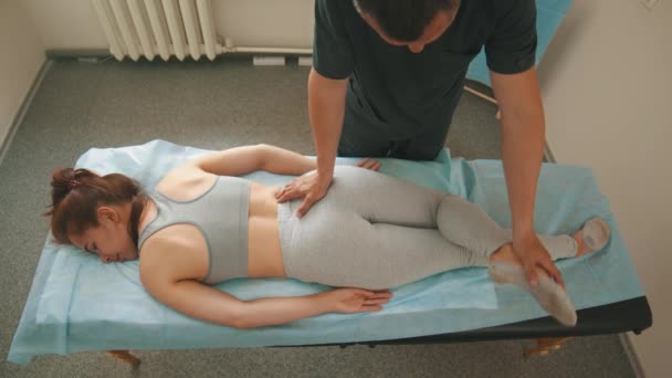 Γυναίκα που έχει μια θεραπεία οστεοπαθητικής - ο γιατρός ζεσταίνει το γόνατό της και το πόδι - σπρώχνοντάς το προς τα πλάγια - Πλάνα, βίντεο