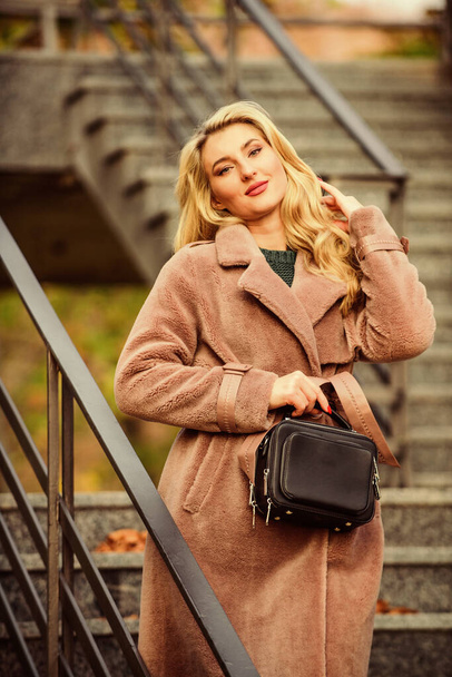 Feeling warm and protected. european winter. girl warm coat stairs background. faux fur coat fashion. stylish business lady leather bag. glamour girl look luxuriously. sexy blong woman. autumn season - Фото, зображення