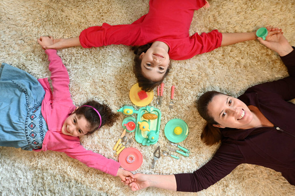 Vue aérienne d'une mère et de ses filles jouant ensemble lors d'un goûter dans une salle de jeux regardant une caméra. De vraies personnes. Espace de copie - Photo, image