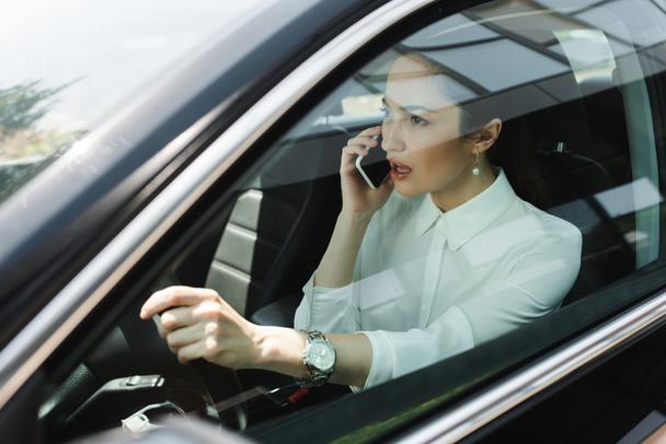 Selective focus of businesswoman talking on smartphone while driving auto  - Фото, зображення