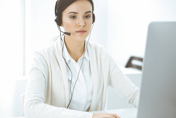 Call center. Casual dressed woman sitting in headset at customer service office. Group of operators at work. Business concept - Foto, Imagen