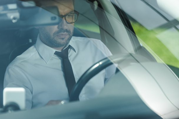 Selective focus of businessman in formal wear driving car  - Foto, afbeelding