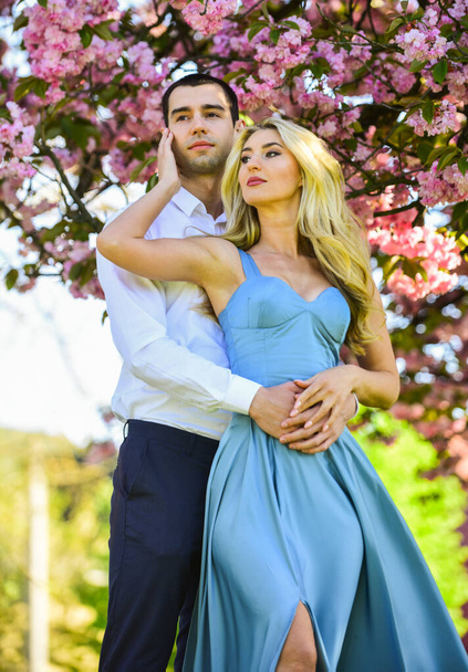 Pleasant time spending. couple in love kiss and embrace. spring flower bloom. man and woman in park with pink blossoming cherry. beauty and fashion. sweet honeymoon. romantic couple under sakura tree - Valokuva, kuva