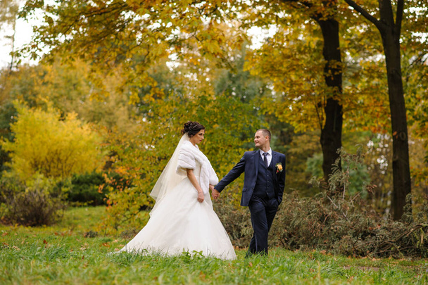 A menyasszony és a vőlegény az őszi park hátterében. - Fotó, kép
