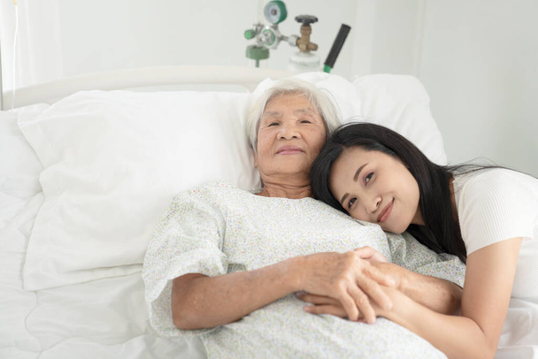 zblízka pacientova dědečka a ženy držící se za ruce v nemocniční posteli - Fotografie, Obrázek