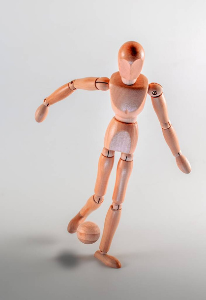 A vertical shot of a wooden figurine playing football isolated on a grey background - Fotoğraf, Görsel