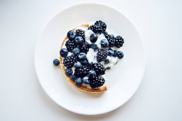 Pastry cake with blueberry and blackberry and yogurt on white plate. Delicious pie  - Photo, Image
