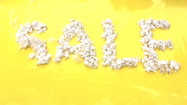 Η επιγραφή Πώληση είναι γραμμένο σε λευκά λουλούδια της πασχαλιάς σε κίτρινο φόντο. Η λέξη Πώληση είναι γραμμένο με πασχαλινά λουλούδια. Λουλούδι επιγραφή Πώληση. Γάμος - Πλάνα, βίντεο