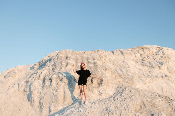Delgado hermosa chica al atardecer sobre la montaña blanca mirando al sol en el verano
 - Foto, Imagen