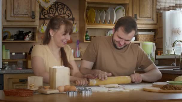 Loving couple sit at the table and roll out yeast-free dough together. - Footage, Video