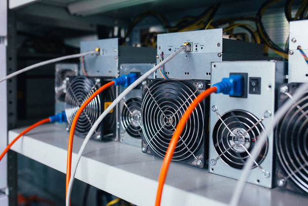 ASIC miners stand on a shelf and connected to electricity and th - Φωτογραφία, εικόνα