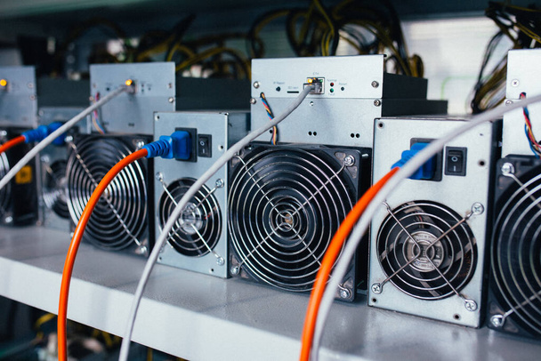 ASIC miners stand on a shelf and connected to electricity and th - Φωτογραφία, εικόνα