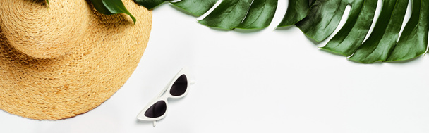 Draufsicht auf grüne Palmblätter, Strohhut und Sonnenbrille auf weißem Hintergrund, Panoramaaufnahme - Foto, Bild
