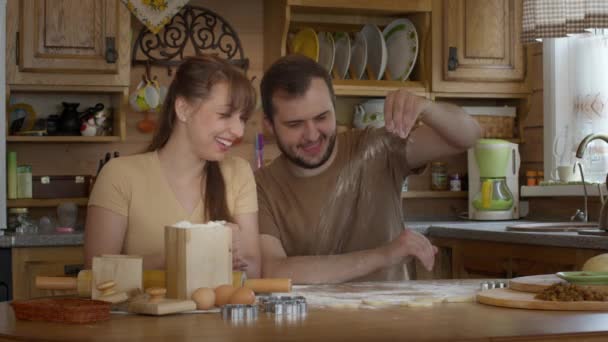 Milující pár sedět u stolu posypat mouku a roll out kvasinek-free těsto - Záběry, video