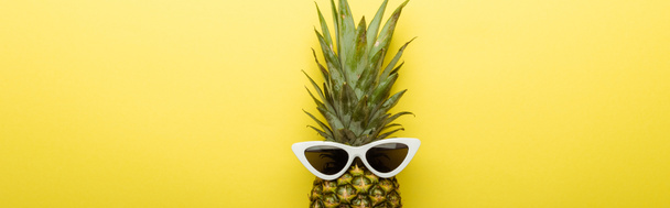 top view of ripe pineapple in sunglasses on yellow background, panoramic shot - Фото, изображение