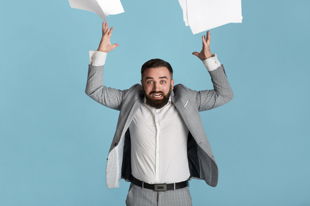 Gestão do stress no trabalho. Angry millennial funcionário do escritório jogando papéis no fundo azul
 - Foto, Imagem