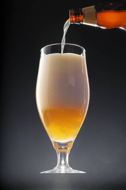 Beer pouring into glass on black background - Fotó, kép