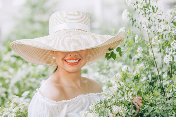Красива стильна жінка в білому капелюсі з квітами на відкритому повітрі портрет
 - Фото, зображення
