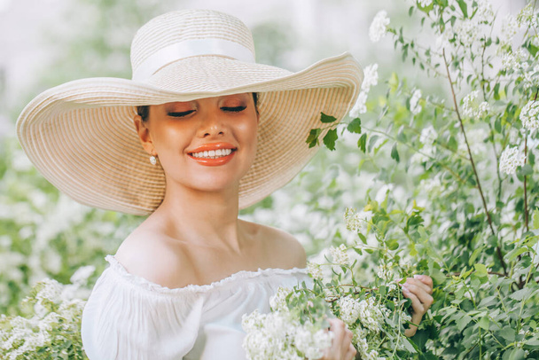Zomer vrouwenportret. Mooi model meisje dragen witte hoed met bloemen outdoor portret - Foto, afbeelding