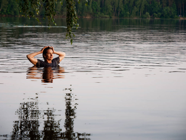 mooi meisje baadt in een meer bij zonsondergang 2020 - Foto, afbeelding