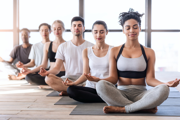 Klasa jogi. Grupa młodych sportowców medytuje z zamkniętymi oczami - Zdjęcie, obraz