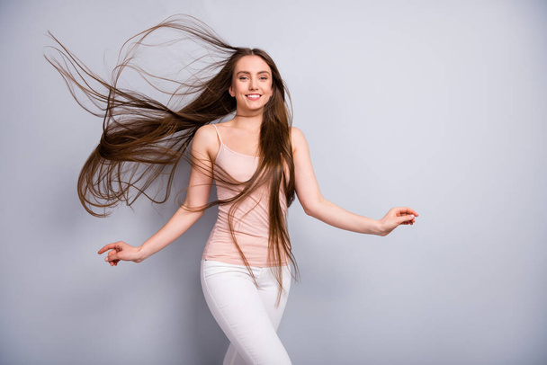 Photo of attractive lady demonstrating ideal neat long healthy hairstyle flying on air after salon walk street graceful wear beige singlet pants isolated grey color background - Fotó, kép