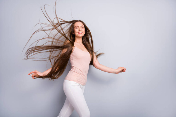 Profile photo of attractive model lady demonstrate neat long healthy hairstyle flying on air after salon walk street graceful wear beige singlet white pants isolated grey color background - Photo, Image
