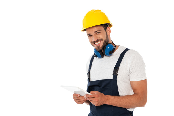 Handsome manual worker smiling at camera and holding digital tablet isolated on white - Photo, Image