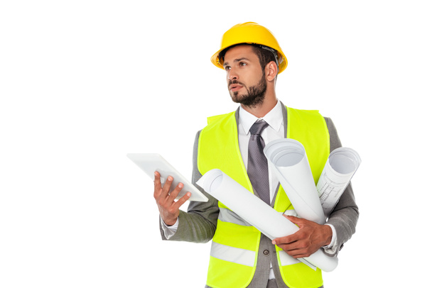 Handsome engineer holding blueprints and digital tablet while looking away isolated on white - Foto, immagini