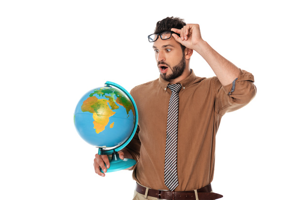 Surprised teacher holding eyeglasses and looking at globe isolated on white - Фото, изображение