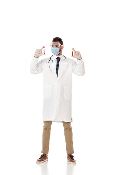 Γιατρός με γυαλιά ασφαλείας και μάσκα κρατώντας δοκιμαστικούς σωλήνες με δείγματα αίματος σε λευκό φόντο - Φωτογραφία, εικόνα