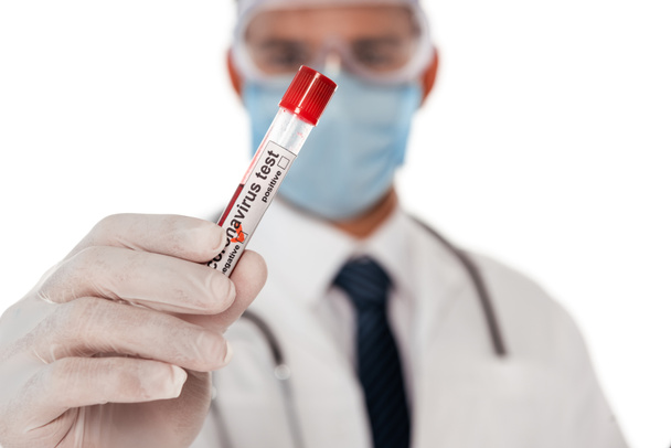 Selective focus of doctor in safety mask and goggles showing test tube with blood sample and coronavirus lettering isolated on white - Photo, Image