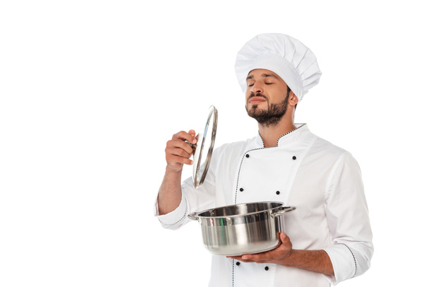 Guapo chef con los ojos cerrados sosteniendo la sartén y la tapa aislados en blanco
 - Foto, Imagen