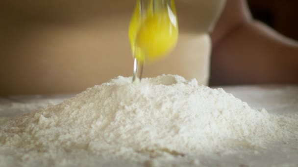 Chiudere cracking uovo crudo sopra la farina sul tavolo in polvere con farina, cottura - Filmati, video