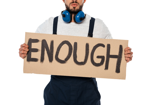 Cropped view of builder in uniform and ear defenders holding signboard with enough lettering isolated on white - Photo, Image