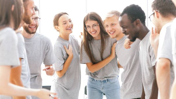 группа счастливых молодых людей, стоящих в светлой комнате - Фото, изображение