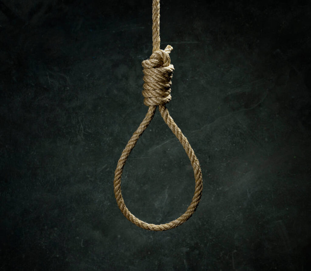 Rope noose for hangman made of natural fiber rope on a grainy gray wall. Hemp rope knot for gallows and Hang man over black concrete wall. The rope noose for homicide or commit suicide concept. - Fotoğraf, Görsel