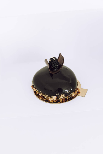 Gourmet chocolate cake with liquid gold and blackberry on top. Food styling dessert in a restaurant. - Valokuva, kuva