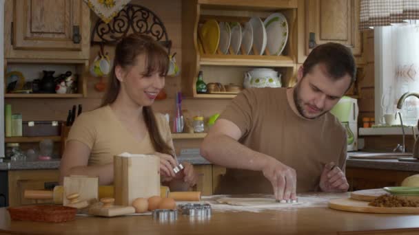 Un homme et une femme découpent des chiffres pour des biscuits dans une pâte. - Séquence, vidéo