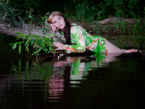Tyttö makaa vedessä vanhan puun oksalla 2020 - Valokuva, kuva