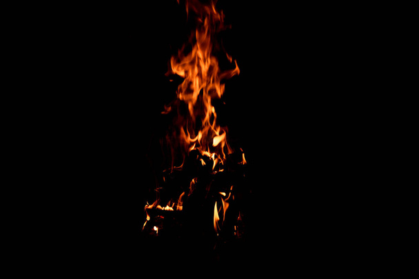 Fényes tűz, fekete háttérrel. A tűz hosszú ideig tartott. Szikrák és lángok. - Fotó, kép