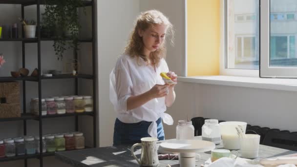 Kobieta garncarka robi ceramiczne naczynia w swoim studio. Proces pracy glazury ceramicznej miski. - Materiał filmowy, wideo